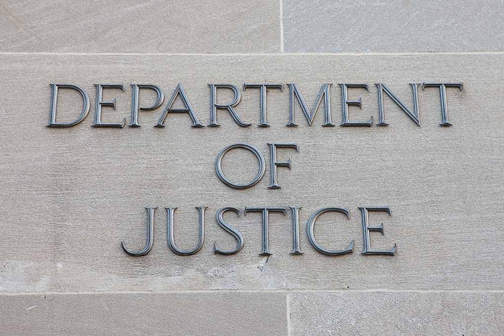 Department of Justice sign on building wall.