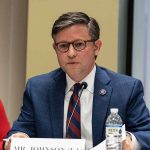 Mike Johnson’s Strategy for Trump’s Comprehensive Agenda: A Single Bill Before Memorial Day Man in suit speaking at a meeting table.