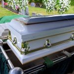 Challenges of Burn Injury Recovery: A Tragic Case from Hawaii and the Role of Specialized Care White coffin at a cemetery with flowers nearby.