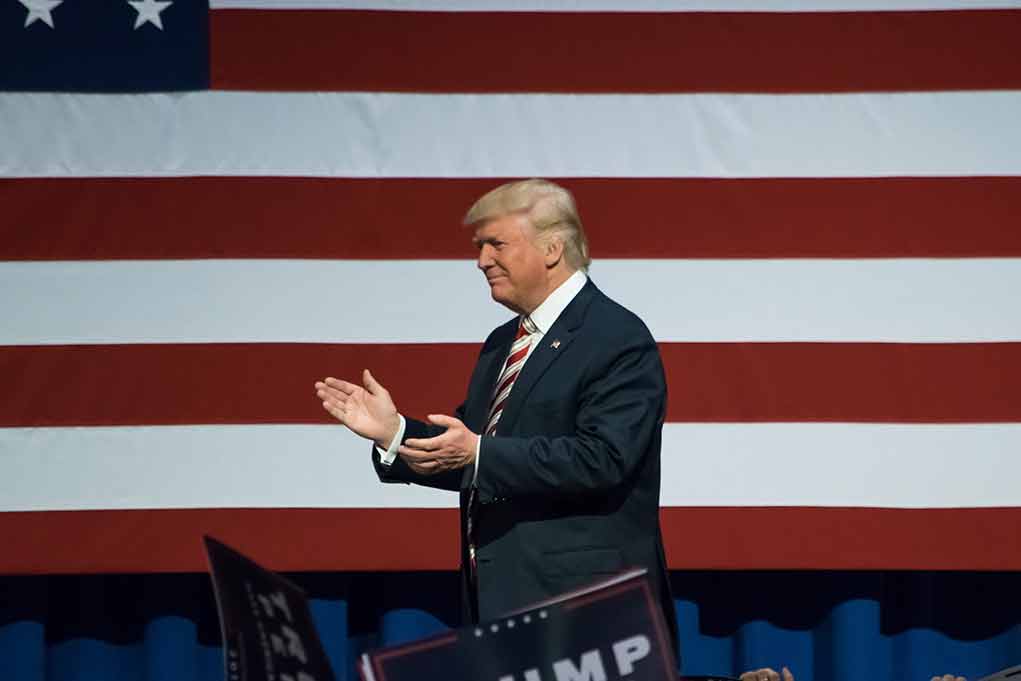Man clapping in front of American flag background