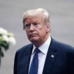 Waters Calls For Melania’s Deportation In Anti-Trump Tirade Man in a suit with an American flag pin.