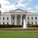 White building with fountain and flower garden front