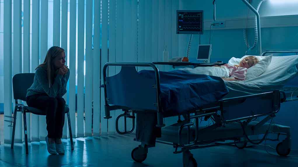 1181842819 featured image Woman sitting beside hospital bed at night