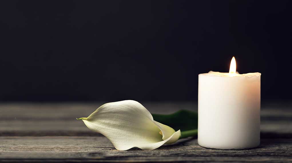1658063071 featured image White candle and calla lily on wooden surface.
