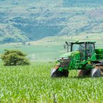 Green tractor working on a lush field landscape