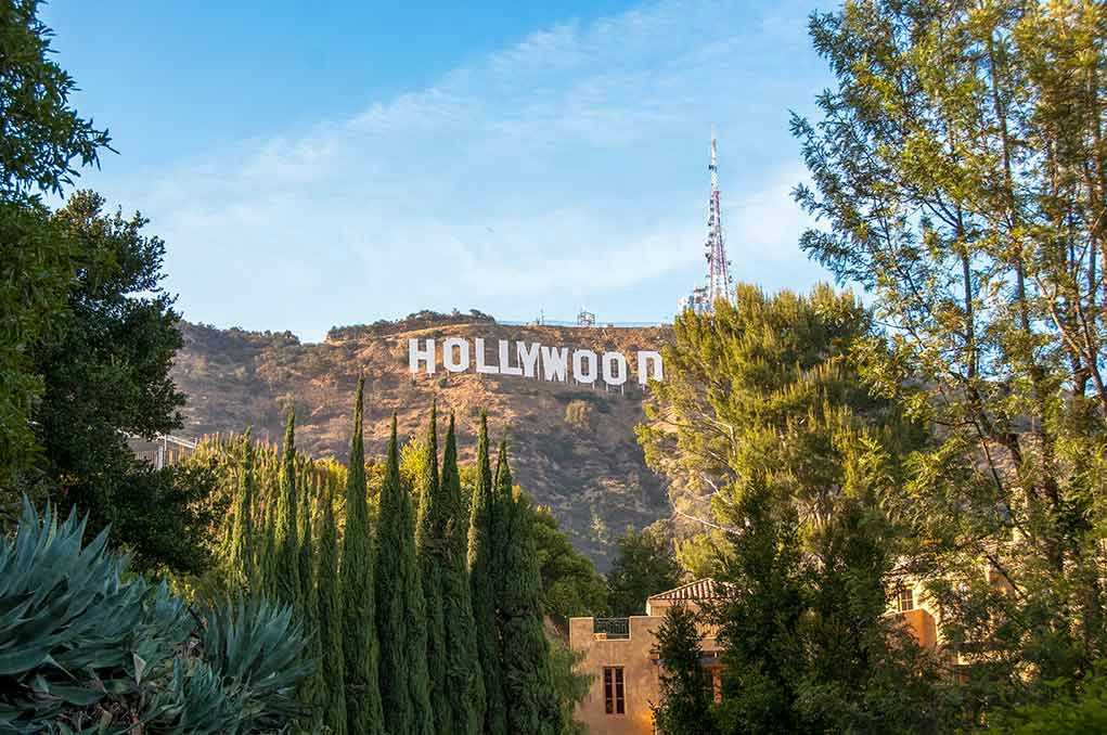 1164563563 Hollywood sign on hill surrounded by trees and buildings