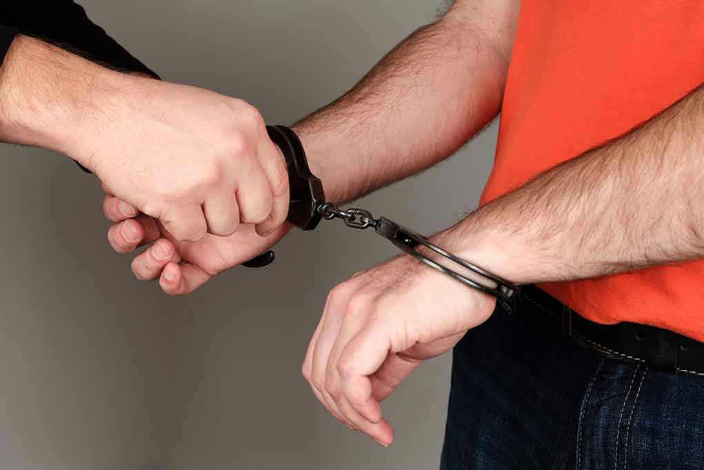 1340097212 Person handcuffing another persons wrists