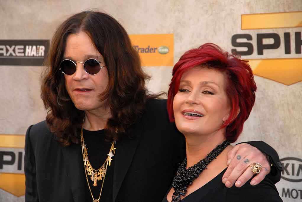 A celebrity couple posing together at a red carpet event smiling and dressed in stylish outfits