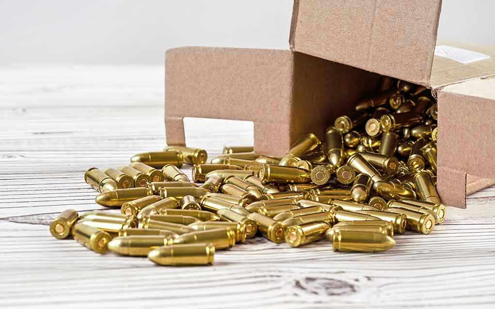 1477517537 Box of brass bullets spilled on wooden surface