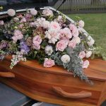 Shocking Loss: Influencer’s Life Ends in Tragedy Coffin with flowers in the back of a hearse.