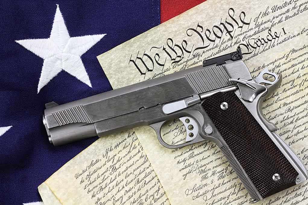 shutterstock_129482747.jpg A handgun placed on top of the U.S. Constitution and an American flag