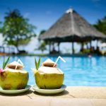 Deadly Bacteria THRIVES In Clean Pools Two coconut drinks with straws beside a swimming pool