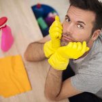 Man in yellow gloves looking frustrated while preparing to clean