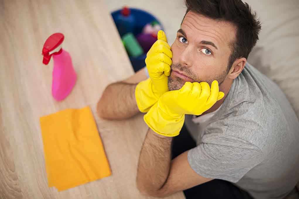 Man in yellow gloves looking frustrated while preparing to clean
