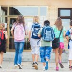Post-Pandemic Reality: Education System EXPOSED Group of children walking towards a school entrance with backpacks
