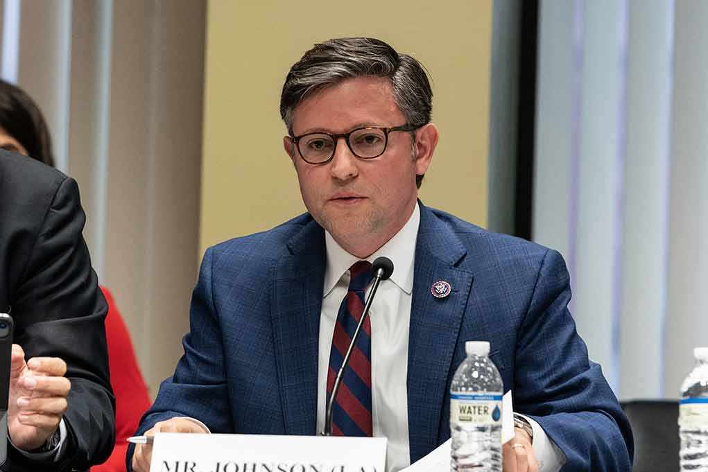 shutterstock_2290525913.jpg A public official speaking at a meeting with a nameplate in front of him