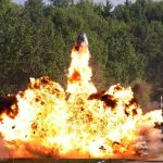 A large explosion with flames and smoke in an outdoor setting