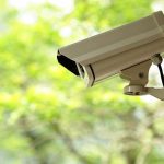 Corporate Giants Rattled — Security Spending SOARS After Multiple Murders A security camera mounted outdoors with a blurred green background