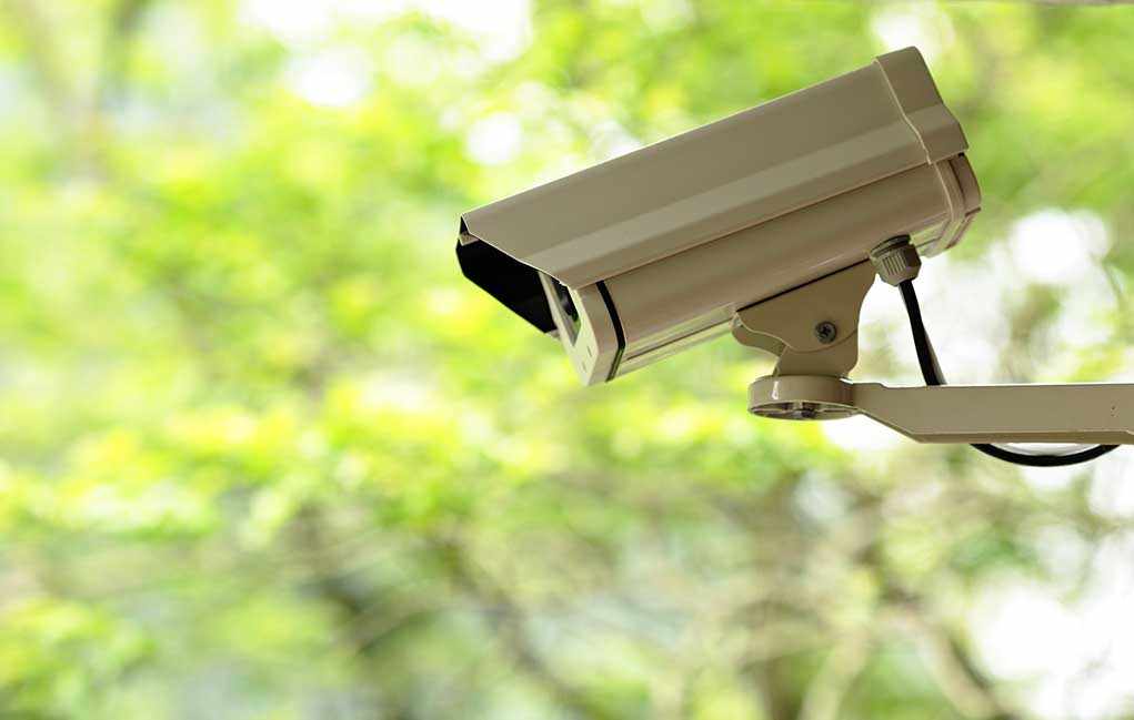shutterstock_75189394.jpg A security camera mounted outdoors with a blurred green background