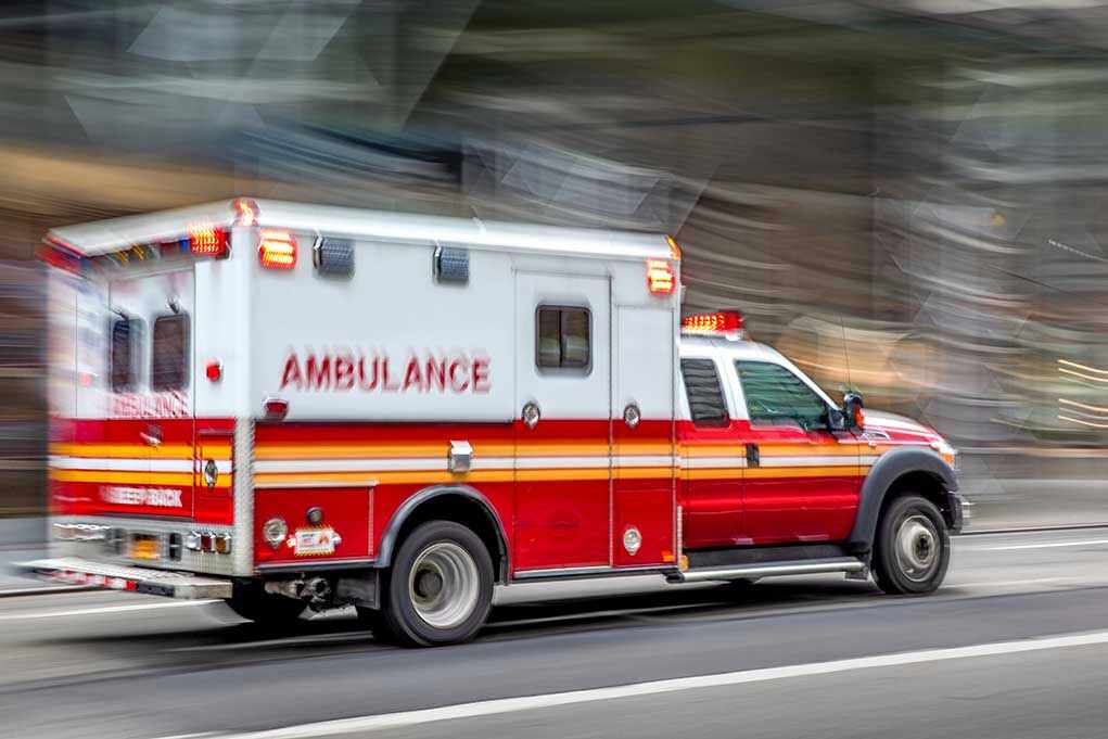 Red and white ambulance driving on street.