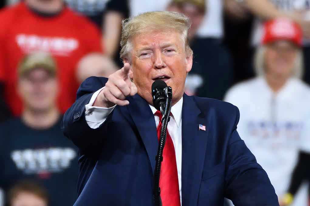 Man in suit pointing, speaking at a rally.