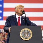 Trump FORCES Iran Cooperation —They’ve AGREED! Man speaks at podium with U.S. flag background.