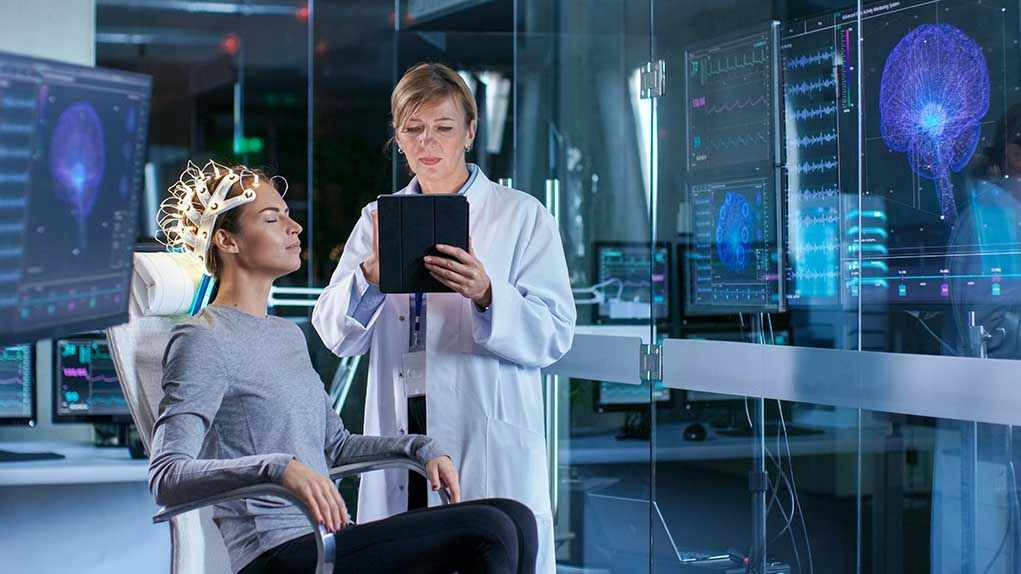 1036798276 Woman undergoing brain scan with doctor monitoring results