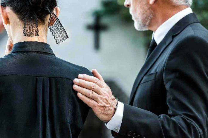 1500621305 Man comforting woman at funeral service.