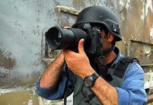 Foreign Diplomatic Crisis—Journalist Held HOSTAGE! Person in helmet taking photos with a large camera.