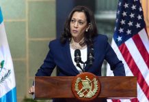 Kamala Sparks Dem Civil War – Even THEY Say No! Person speaking at podium with flags in background.