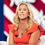 GOP ABANDON Own Nominee For Dem – MTG Explodes! Woman speaking at an event, wearing a red dress.