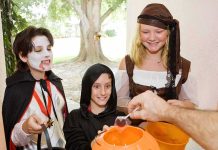 Children in Halloween costumes collecting candy from a house