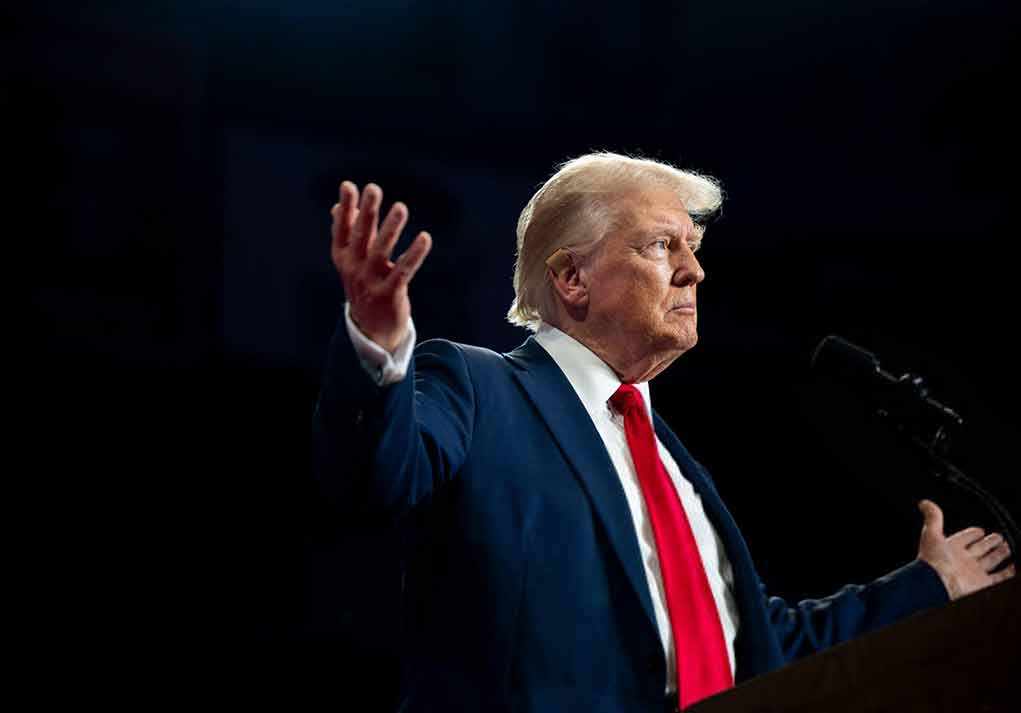 A man in a suit gesturing during a speech