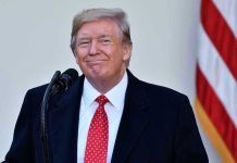 Trump REVERSES Oil Blockade – Drill Baby, Drill! Man in suit and tie speaking at podium.