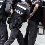 Sting Operation Strikes: 150+ ARRESTED! Police officers arresting a handcuffed person.