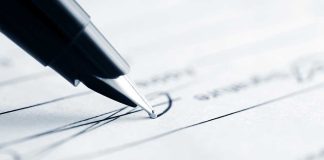 Close-up of a pen poised above a document with handwritten lines
