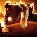 NBA Coaches Home ERUPTS—Total Destruction A firefighter battling a large house fire at night