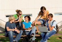 Group of students sitting on a bench outdoors, engaged in study and discussion