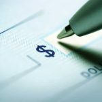 Record-Breaking Auction: Titanic Watch Price Stuns World Close-up of a pen poised over a check with a dollar sign