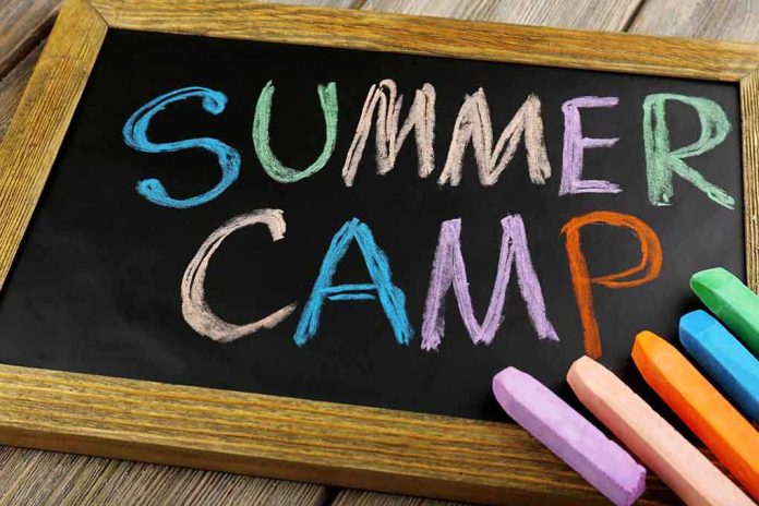 Chalkboard with colorful writing that says Summer Camp and several pieces of chalk