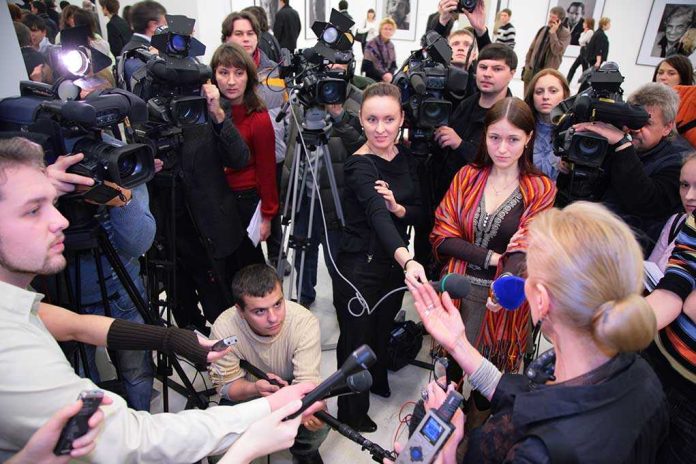 A crowded press conference with journalists and cameras surrounding a speaker
