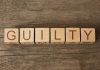 Wooden blocks arranged to spell 'GUILTY' on a wooden surface