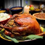 A beautifully roasted turkey on a festive table surrounded by side dishes and decorations