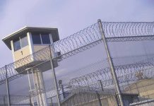 Disgraced Celebrity RELEASED From Prison – Paparazzi Waiting Guard tower behind barbed wire fence in a prison.