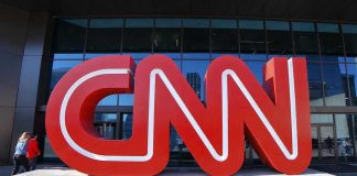 Large red CNN sign outside building entrance.