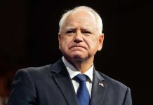 Somali Group Taunts Taxpayers Amid Billion-Dollar Fraud Scandal Man in suit with a U.S. flag pin.