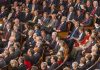 House Leaders CANCEL Vote – Crucial Bill Dies Mysteriously Audience of officials sitting and reading documents in auditorium.
