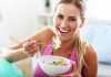 Woman smiling and eating a salad bowl.