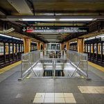 Subway station platform with directional signs overhead.