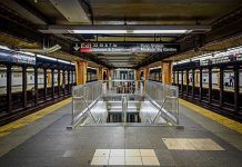 Subway station platform with directional signs overhead.